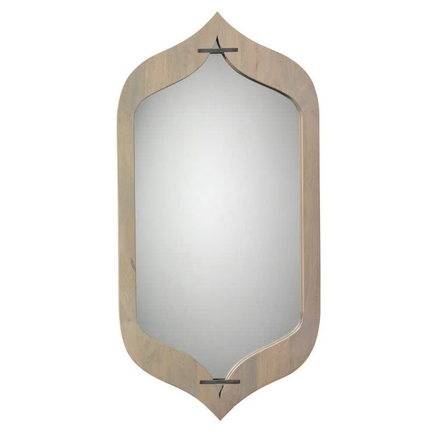 An irregularly shaped mirror with a gray washed wooden frame and antique silver-tone metal details.