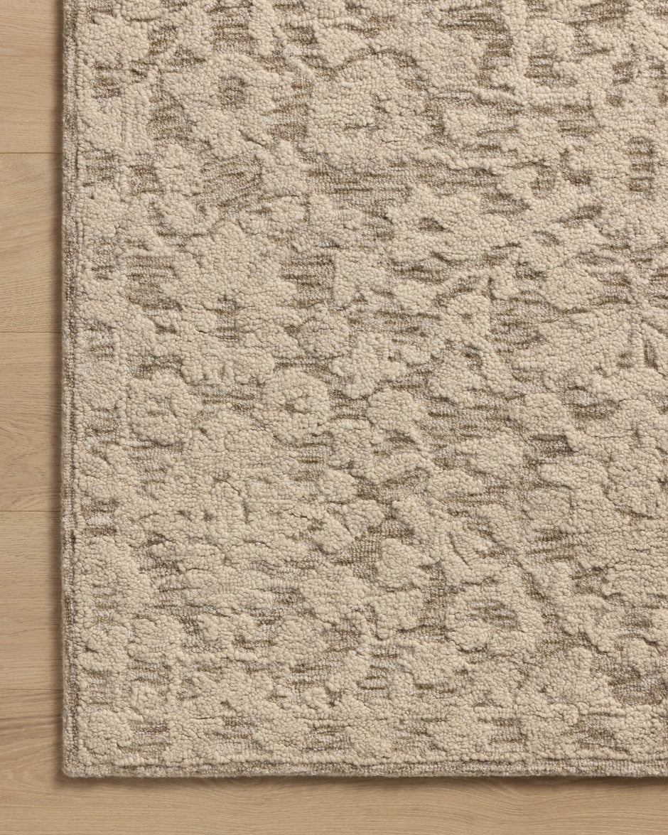 Close-up of a corner of a Loloi Prudence rug showing a hand-tufted floral pattern in stone and ivory colors.