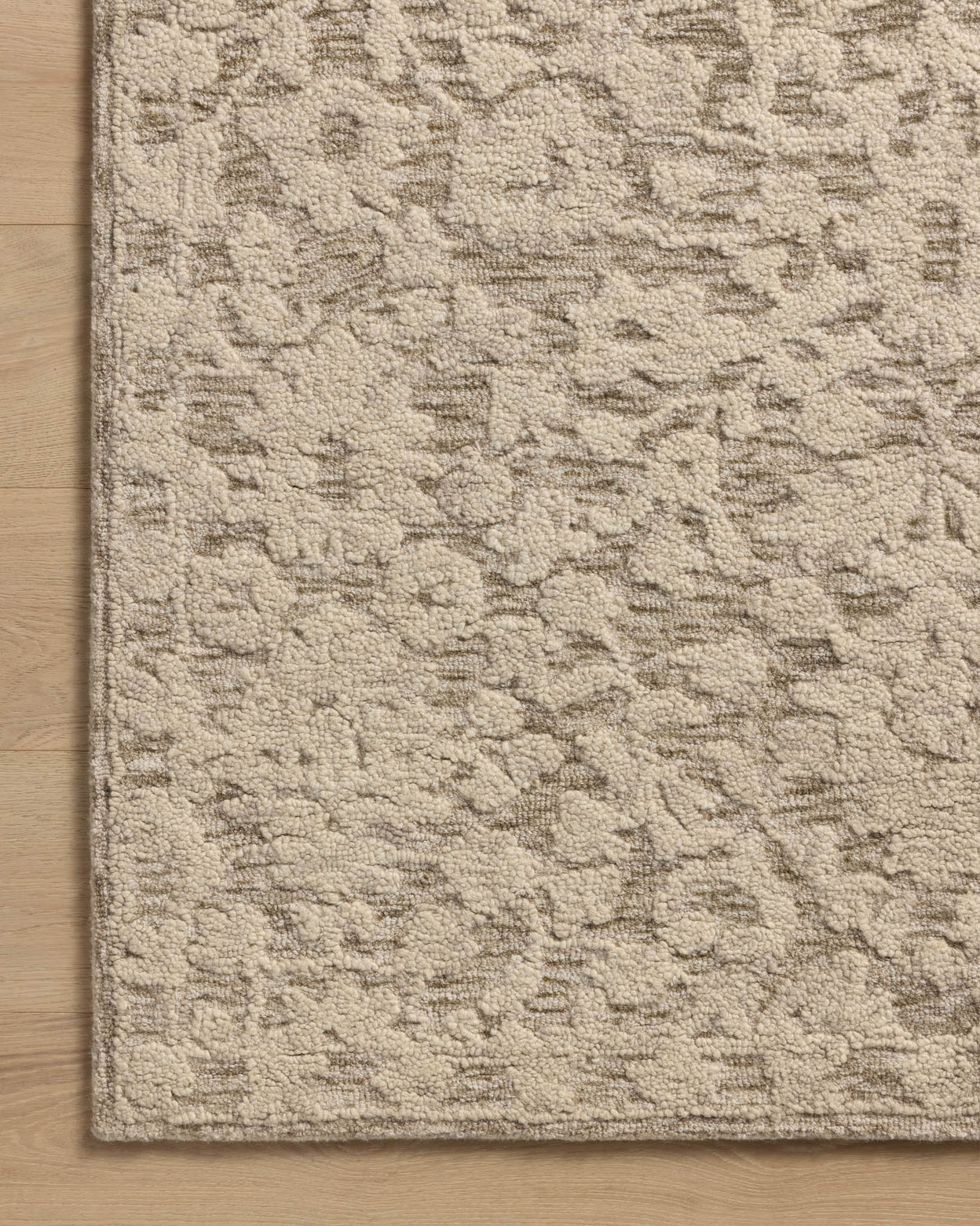 Close-up of a corner of a Loloi Prudence rug showing a hand-tufted floral pattern in stone and ivory colors.