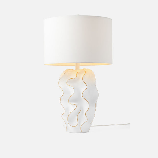 A Bethany table lamp with a textured matte white and gold resin base, topped with a white linen shade, on a white background.