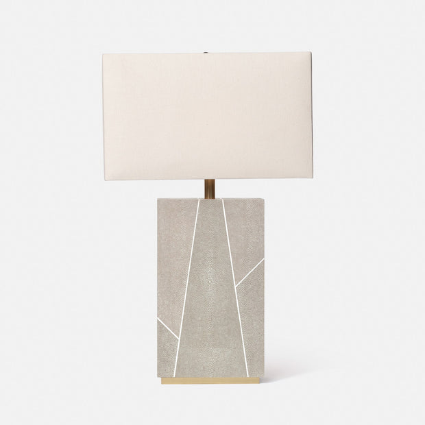 A rectangular table lamp with a beige shade, featuring a geometric patterned base in shades of gray and white, topped with a gold accent.