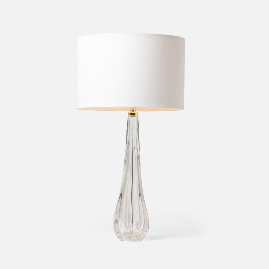 A table lamp with a clear, faceted glass base and a white linen shade.
