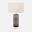 A table lamp with a bubble glass shade in gray, brass hardware, and a white marble base.