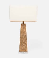 A table lamp with a rustic gold leaf resin column and a rectangular linen shade, with a clear acrylic base.