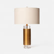 A table lamp with a brass base, clear crystal column, and a white lampshade.