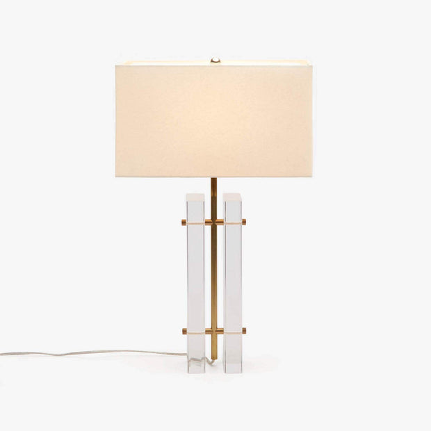 A Ryan table lamp with clear acrylic panels and a brass tube center column, topped with a beige rectangular lampshade.