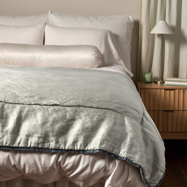 Bella Notte Paloma silk charmeuse throw blanket with a soft, luxurious cloud-colored fabric, perfect for cozy bedroom decor.