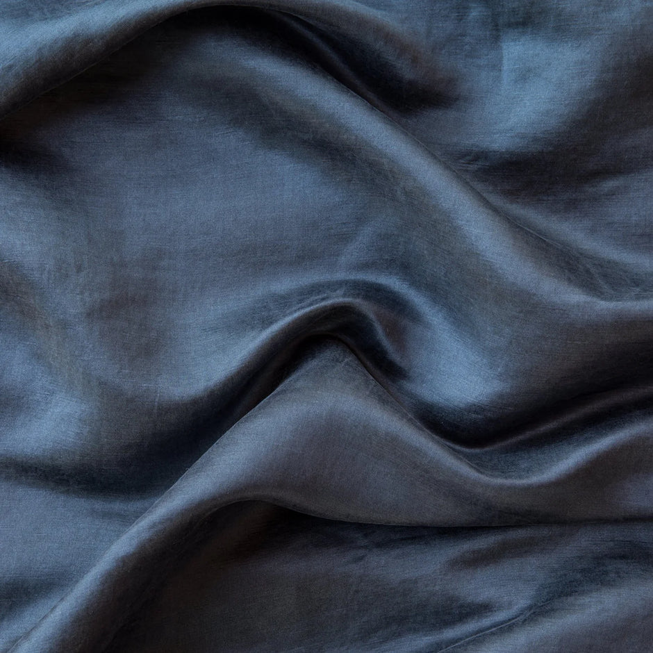 A dark navy silk blanket with a subtle velvet trim, draped elegantly.