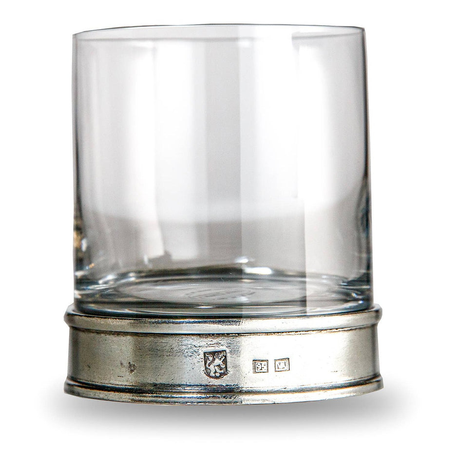 A clear round glass lowball glass with a pewter base, featuring the Arte Italica logo, hand made in Italy.