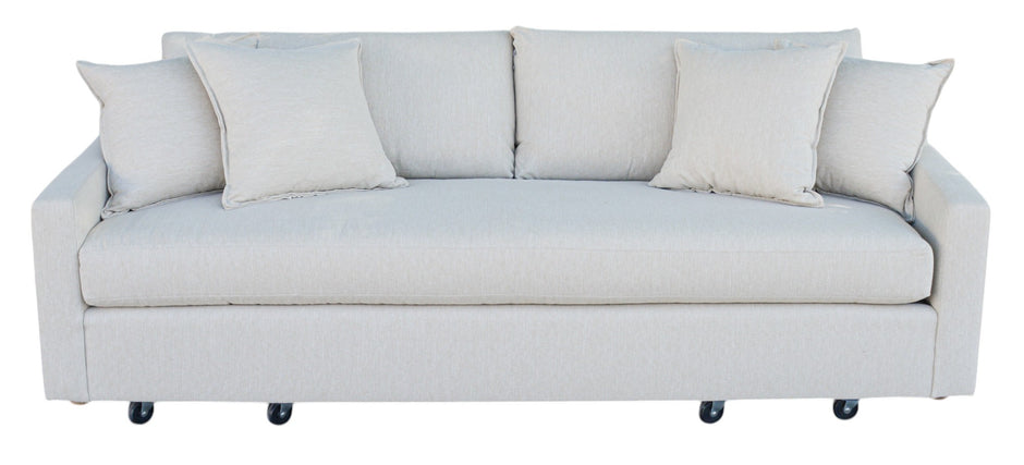 A 'Verellen Thibaut Sofa Amelia Bisque' with beige upholstery, featuring slightly tapered arms, low tight seat, and plush back cushions, on caster wheels.