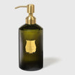 A green, ribbed glass bottle with a gold-colored pump, labeled 'Trudon', containing hand soap.