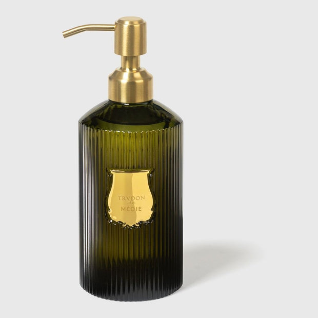 A green, ribbed glass bottle with a gold-colored pump, labeled 'Trudon', containing hand soap.