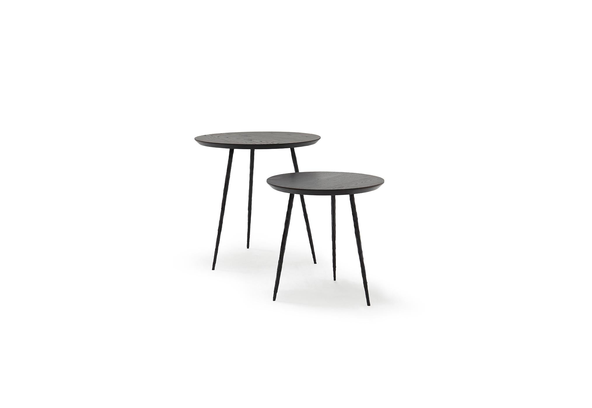 Two round walnut nesting tables with hand-hammered steel legs, one larger than the other, on a white background.