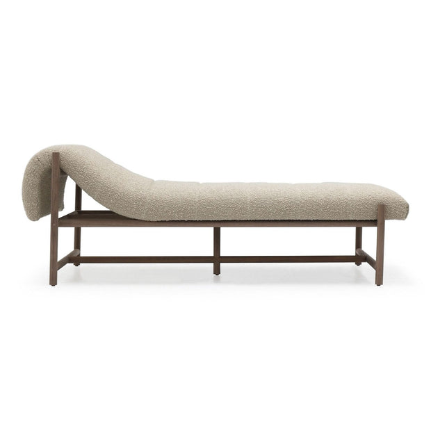 A beige upholstered daybed with a walnut wood frame, featuring a sleek, curved design.