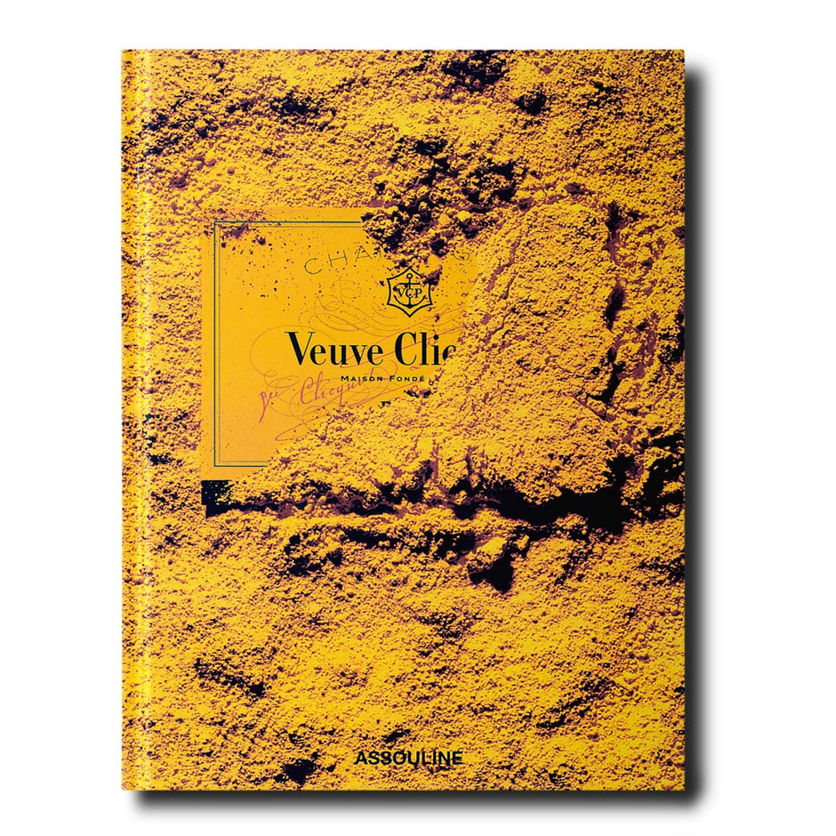 Assouline Veuve Clicquot decorative book featuring vibrant yellow and black design, placed on a wooden surface.