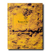 Assouline Veuve Clicquot decorative book featuring vibrant yellow and black design, placed on a wooden surface.
