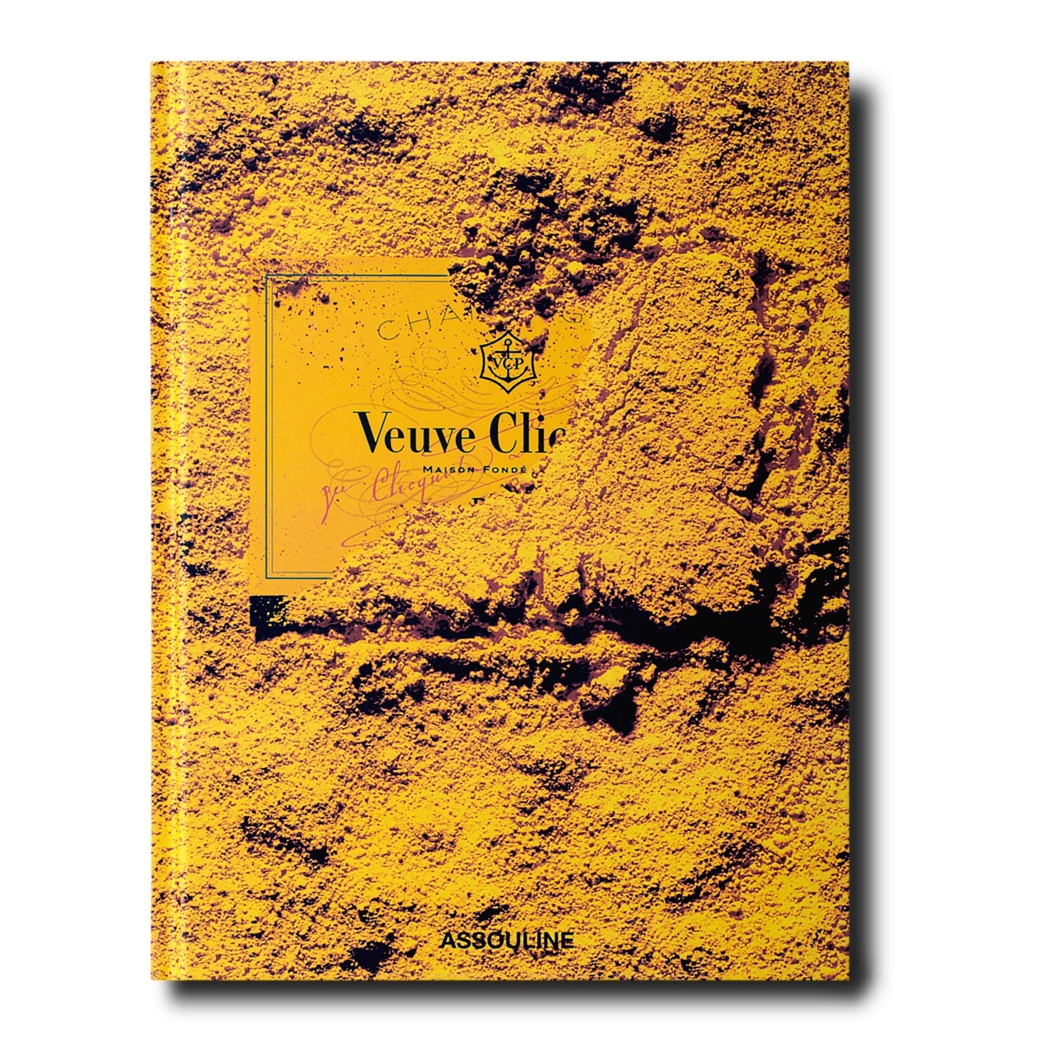 Assouline Veuve Clicquot decorative book featuring vibrant yellow and black design, placed on a wooden surface.