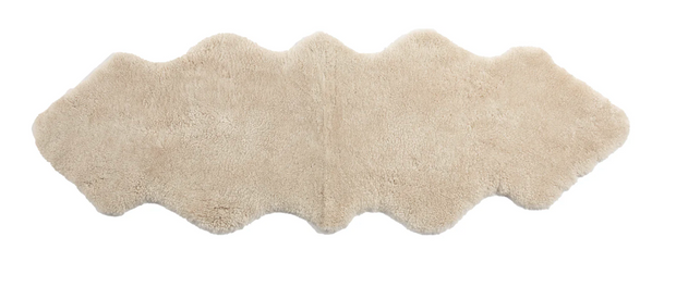 Beige area rug made from sheepskin with a wavy pattern on a white background