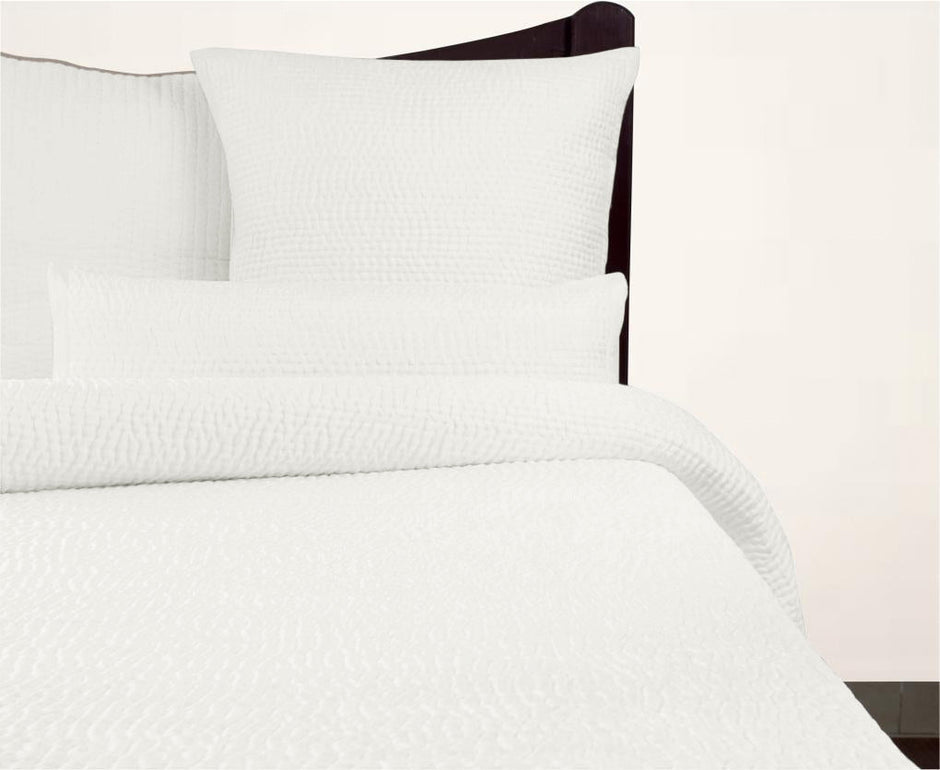 Cream Avasa Katherine quilt spread with intricate stitching, neatly folded to showcase its soft, luxurious fabric and elegant design.
