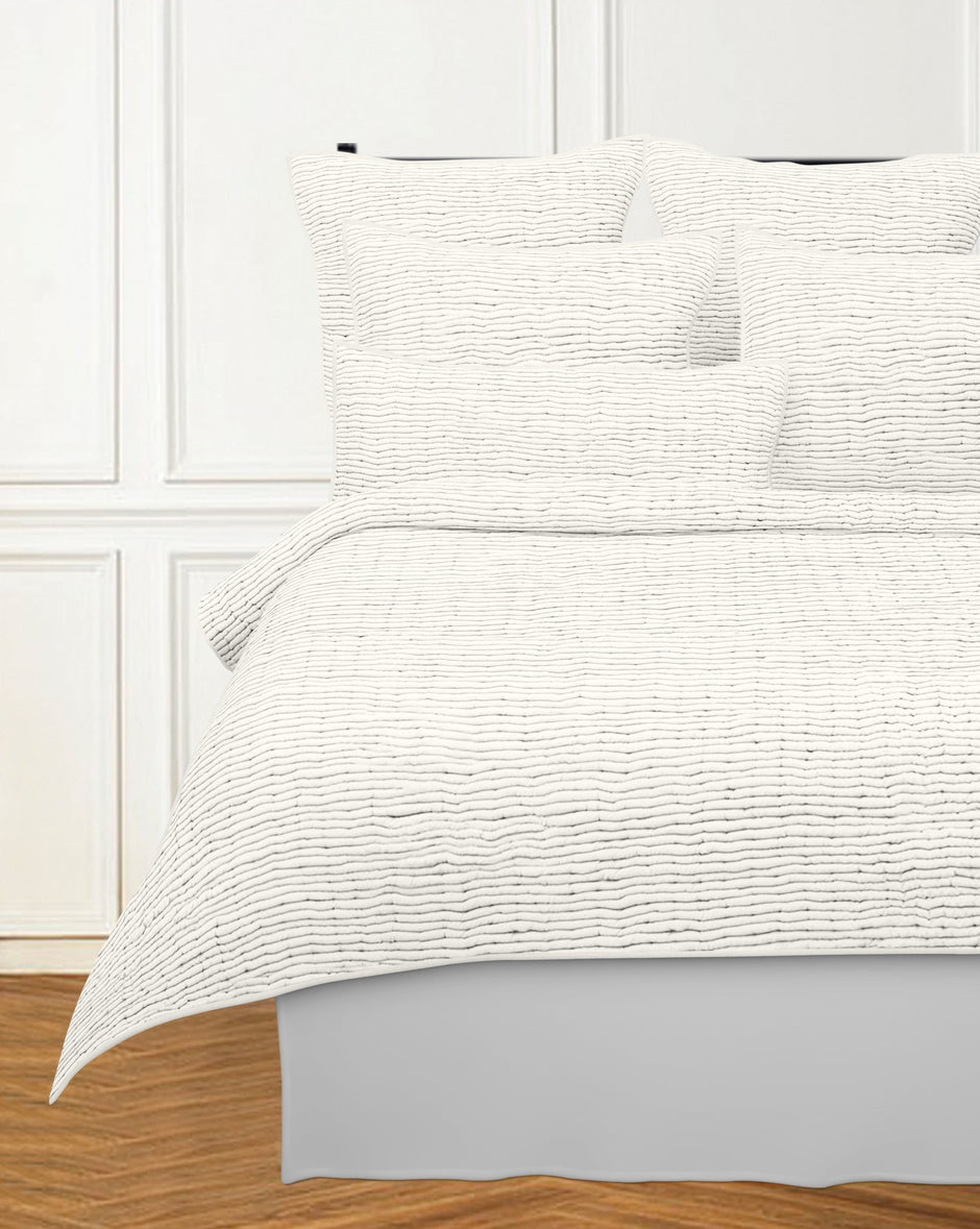 Cream Avasa Ridge Quilt perfectly displayed on a bed, showcasing its soft fabric and elegant design.