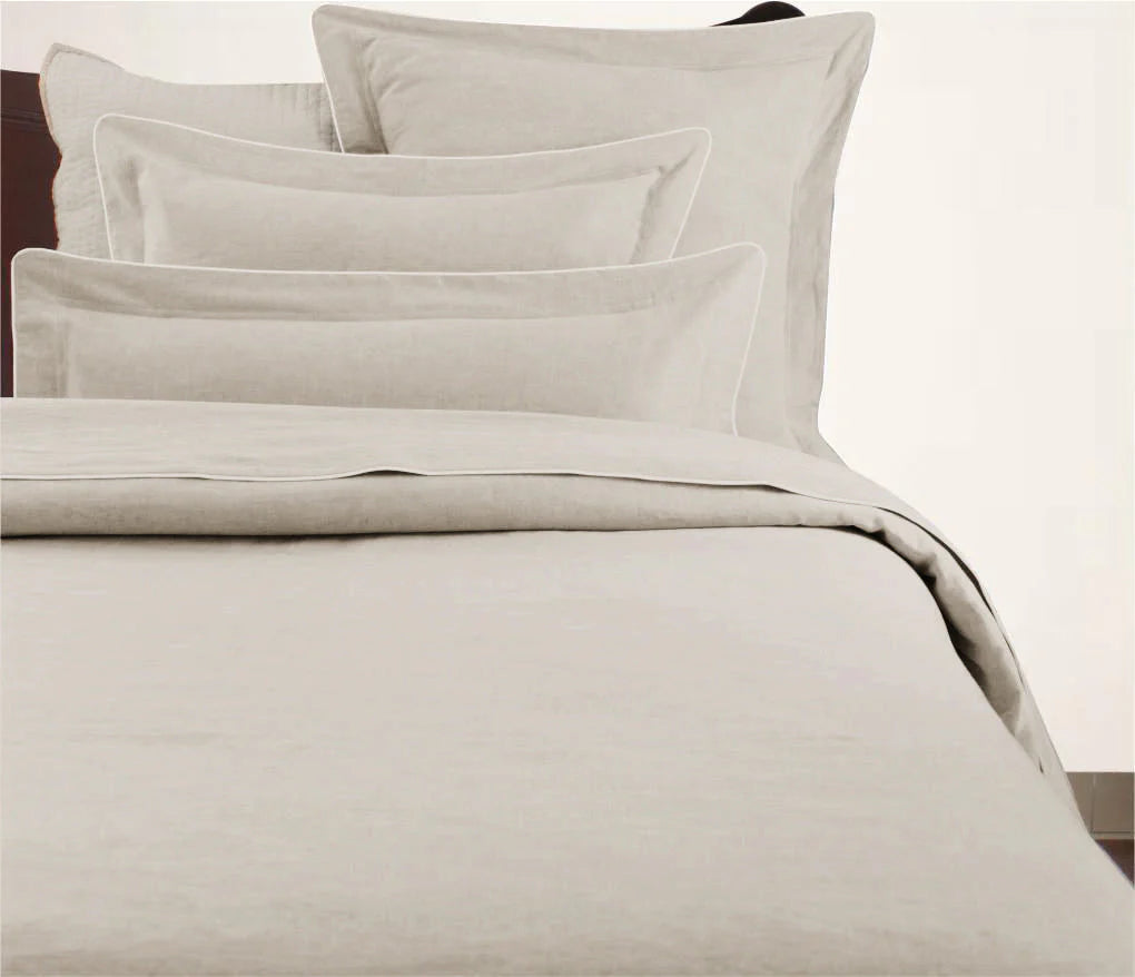 A beige duvet cover with a corded edge, displayed on a bed.