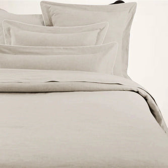 A beige duvet cover with a corded edge, displayed on a bed.