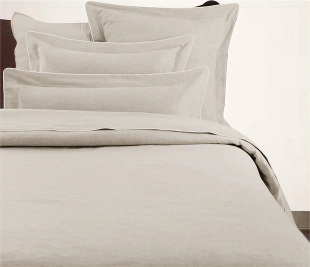A beige duvet cover with a corded edge, displayed on a bed.