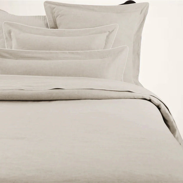 A beige duvet cover with a corded edge, displayed on a bed.