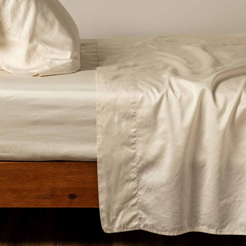 Bella Notte Bria flat sheet in natural color, showing smooth fabric and clean edge details on a neatly made bed.