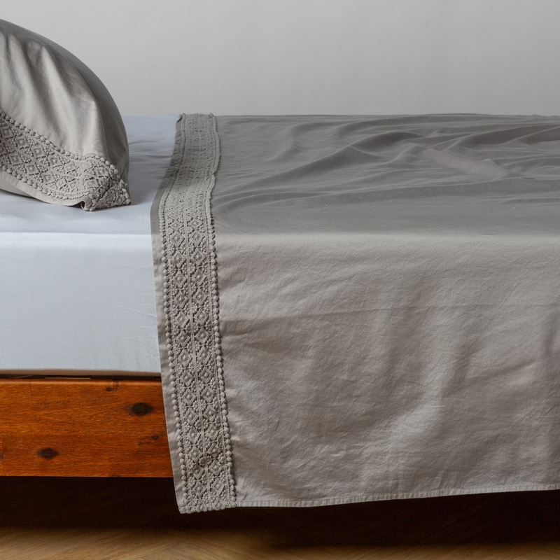 Bella Notte Bria flat sheet in Cenote with Novola lace, showcasing soft fabric and elegant lace trim on a neatly made bed.