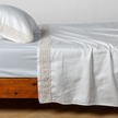 Bella Notte Bria flat sheet in Cenote with Novola lace, showcasing soft fabric and elegant lace details on a king-size bed.