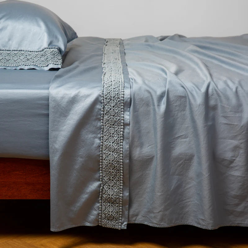 Bella Notte Bria flat sheet in Cenote with Novola lace, showcasing soft fabric and elegant lace details on a neatly made bed.