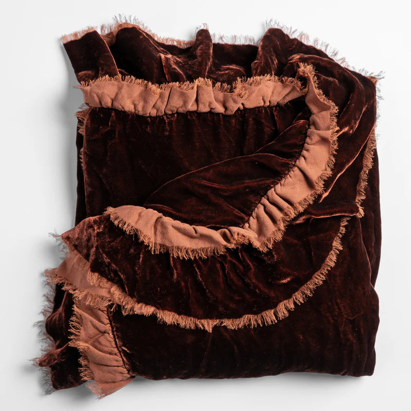 Bella Notte Loulah throw blanket in warm autumn tones, soft and cozy fabric, draped over a stylish living room sofa.