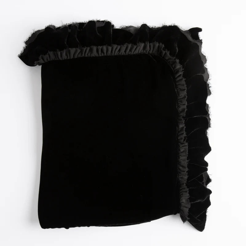 Bella Notte Loulah Throw Blanket draped over a cozy armchair, showcasing its soft, luxurious fabric and warm autumn tones.
