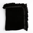Bella Notte Loulah Throw Blanket draped over a cozy armchair, showcasing its soft, luxurious fabric and warm autumn tones.