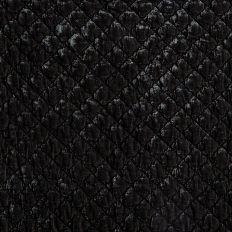 Bella Notte silk velvet quilted throw blanket draped over a sofa, showcasing its luxurious texture and rich autumn colors.