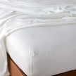 In Stock Bella Notte Madera Luxe fitted sheet in Winter White on Eastern King bed, showcasing soft, luxurious bedding fabric