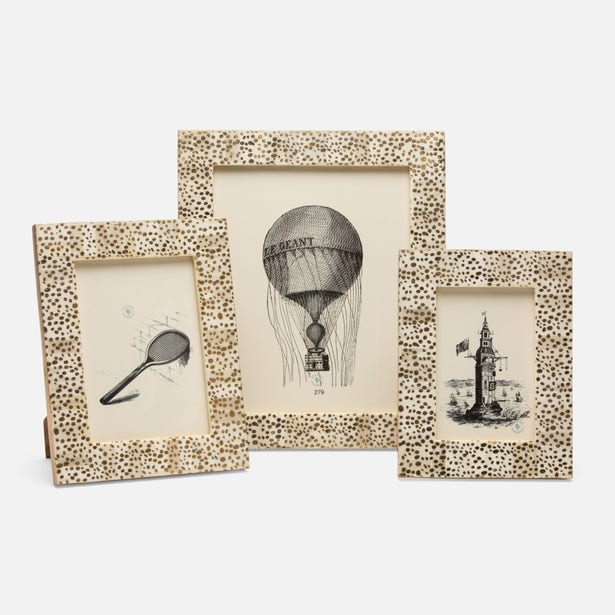 A set of three picture frames with a spotted gold design on a bone base, displayed with different images inside them.