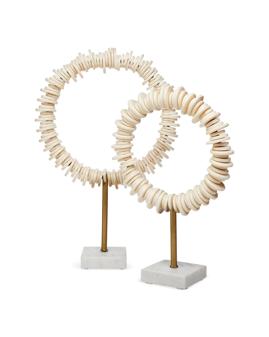 Two decorative circular sculptures made of stacked natural wood discs on slender brass stands with square white marble bases, photographed against a clean white background.