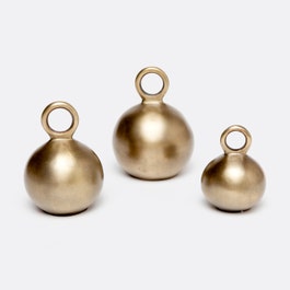Made Goods Anton gold iron kettle bells set of 3 on a tray, showcasing their shiny metallic finish and decorative design.