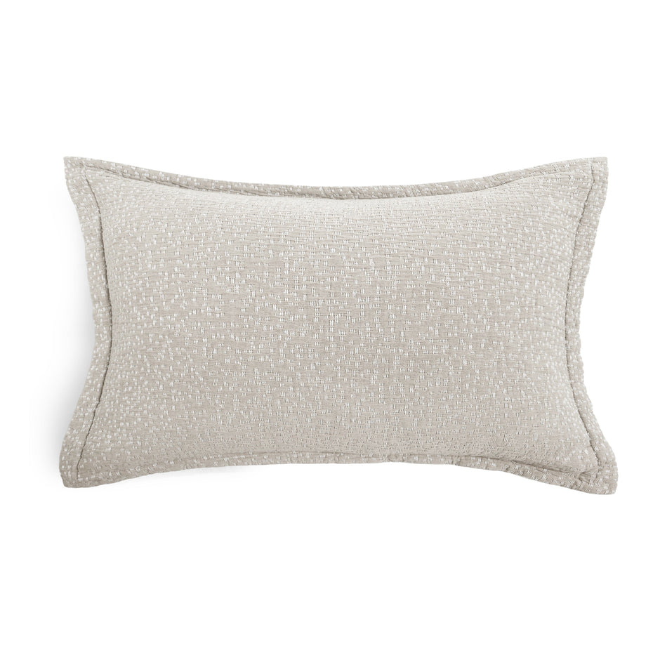 A rectangular lumbar throw pillow in a textured light beige fabric with piped edges, shown on a plain white background.