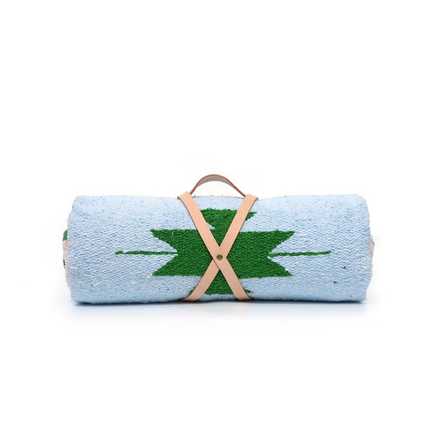 Rolled-up towel with green leaf design and brown strap on a white background