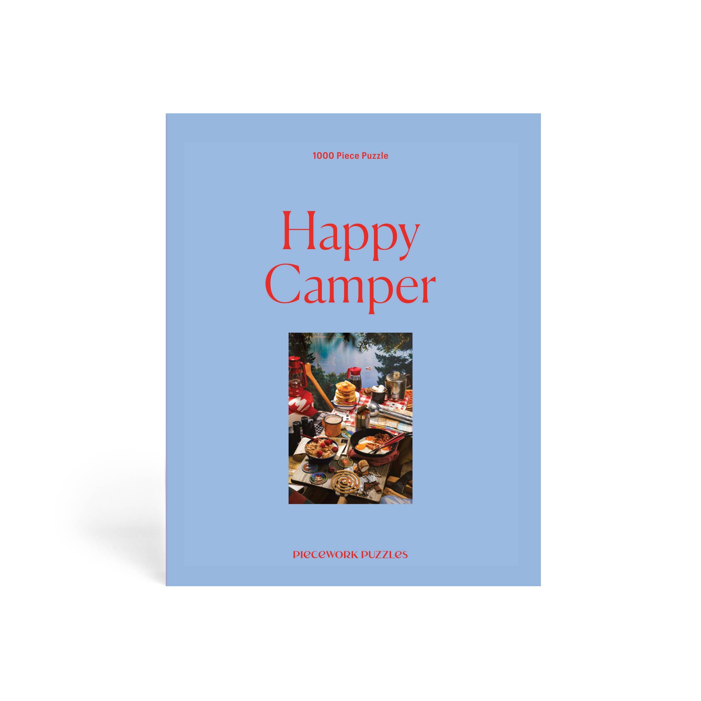 1000-piece Happy Camper puzzle by Piecework featuring a colorful camping scene with tents, trees, and a cheerful outdoor setting.
