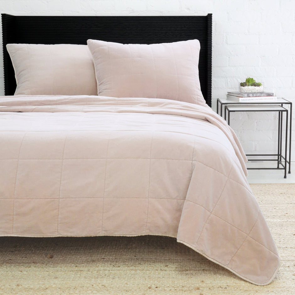 Blush Pom Pom at Home Amsterdam coverlet on a bed, showing soft fabric and decorative pom pom trim for a cozy bedroom look.