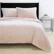 Blush Pom Pom at Home Amsterdam coverlet on a bed, showing soft fabric and decorative pom pom trim for a cozy bedroom look.