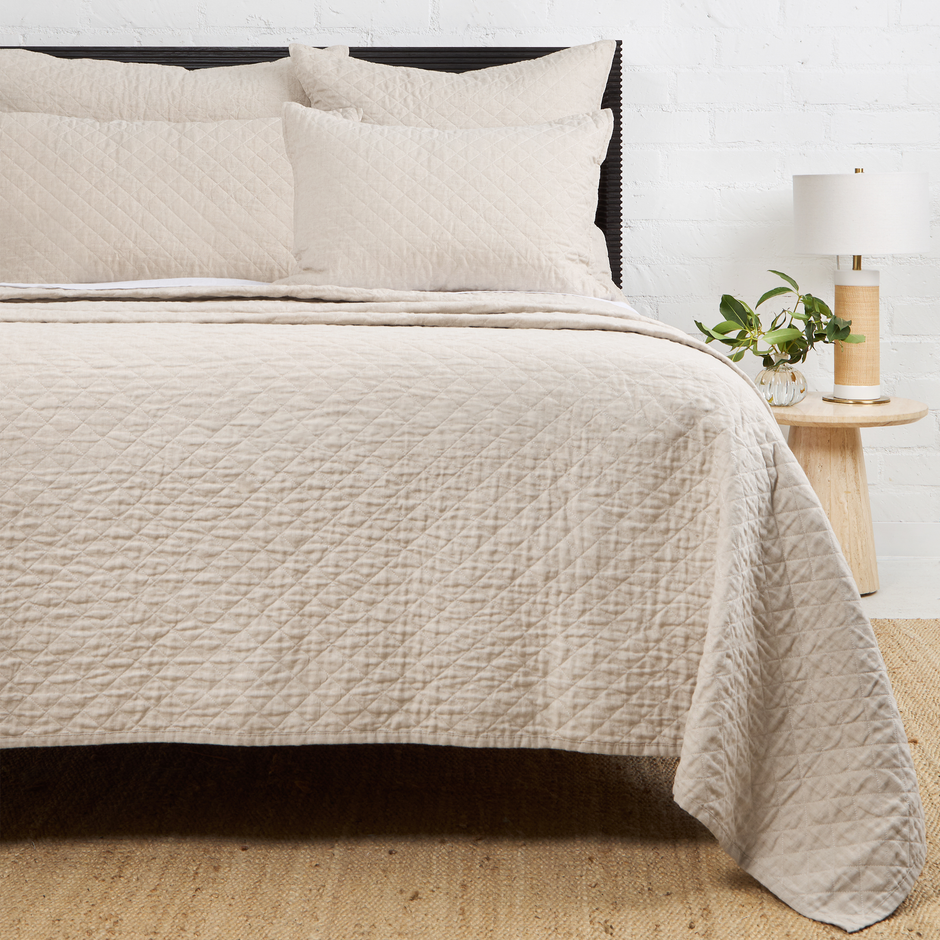 Navy Pom Pom at Home Hampton coverlet on a bed, showcasing soft fabric and decorative pom pom edges for a cozy bedroom look.
