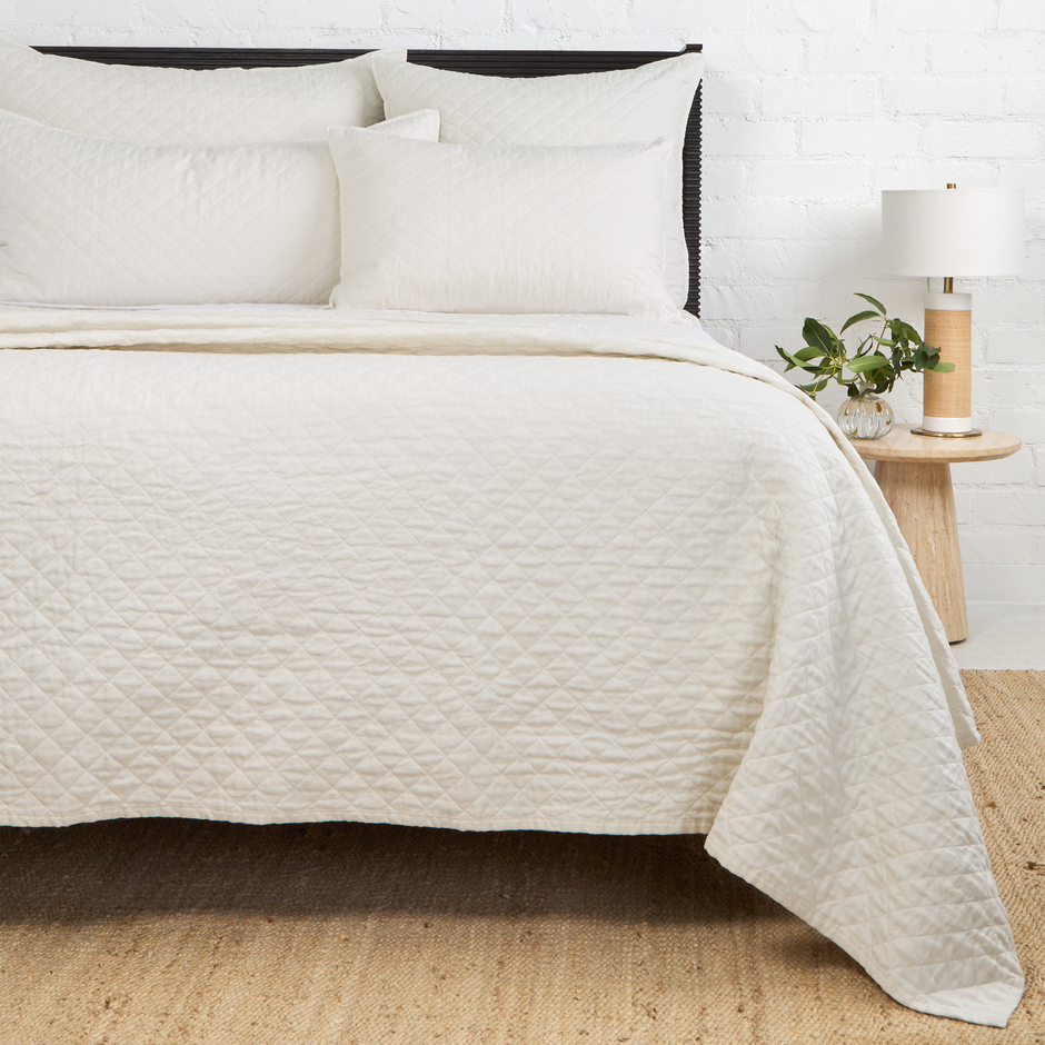 Navy Pom Pom at Home Hampton coverlet on a bed, showcasing a soft, textured fabric with pom pom accents for a cozy bedroom look.
