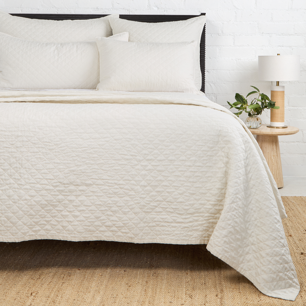 Navy Pom Pom at Home Hampton coverlet on a bed, showcasing a soft, textured fabric with pom pom accents for a cozy bedroom look.