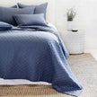 Navy Pom Pom at Home Hampton coverlet on a bed, showcasing its soft fabric and decorative pom pom trim for a cozy bedroom look.