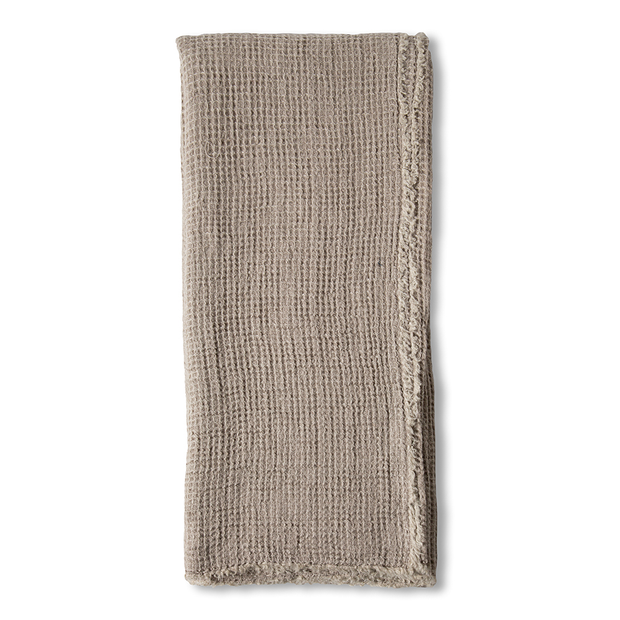 Taupe linen throw blanket by Pom Pom at Home with decorative pom-pom accents, perfect for cozy home decor.